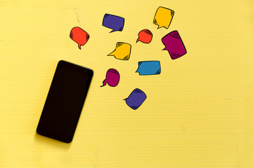 Smartphone on yellow background with text bubbles around. Messaging, texting and connection concept