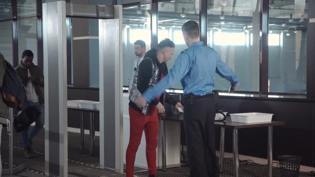 Employees checking passengers at counter with gates passing border control at airport.