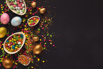 Colorful easter eggs and sprinkles on black background