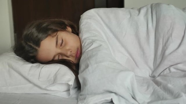 Little cute girl sleeping in bed. little girl teen brunette asleep on the bed indoors lifestyle