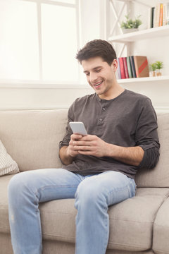 Young man messaging on smartphone at home