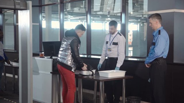 Officer throwing away forbidden things out of passenger cabin baggage standing at counter in airport.