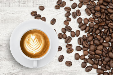 Coffee cup and roasted coffee beans on wood background.