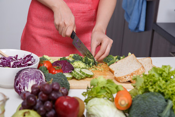 hand using knife to cutting broccoli in kitchen room