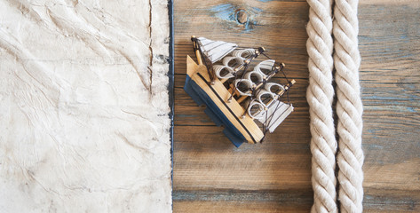 old paper, rope and model classic boat on wood background