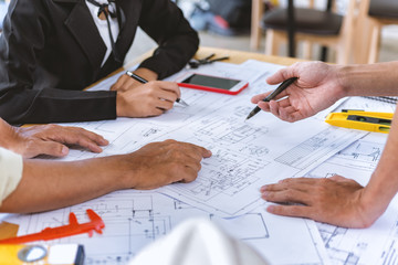 Team engineer meeting for colleagues discussing and checks construction blueprints on new project at desk in office.