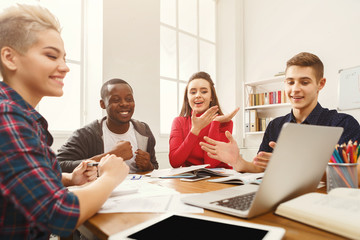Group of diverse students studying at wooden table