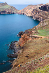 Beautiful blue bay surrounded by rocky cliffs during the sunny day in Madeira island, Portugal