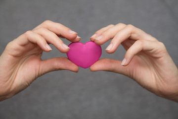 St Valentine symbol: woman's hands holding a little heart next to the chest where a real heart is situated