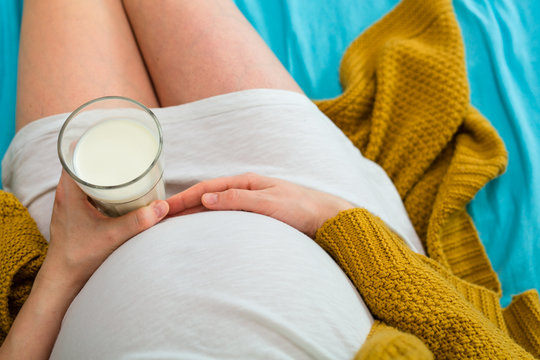 Pregnant woman drinking milk. Aerial close up view.