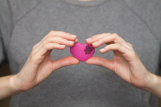woman's hands holding a little heart next to the chest where a real heart is situated