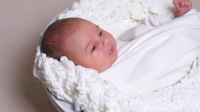 Portrait of newborn baby with big blue eyes laying on white blanket