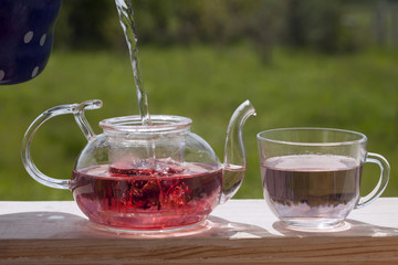 Teapot with fragrant herbal tea on a background of nature