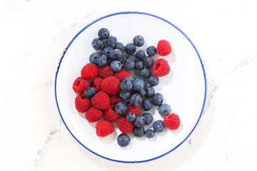 plate with berries on a white background, top view