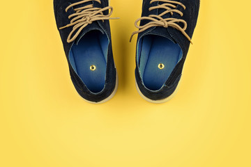 Abstract men's shoes with paper pins on yellow. Pranks and tricks concept for April fool's day