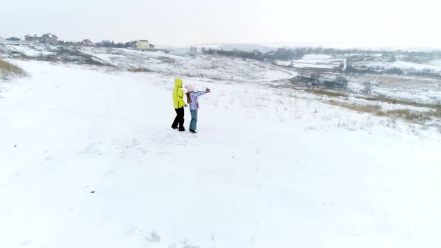 Happy mother and little daughter entertaing together outdoors during winter holidays, aerial view