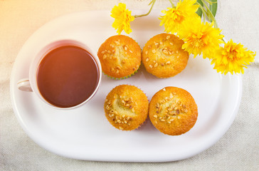 Cup hot cocoa or hot chocolate and banana cupcake in white plate on table with yellow fake flowers with sunshine in the morning background, Concept time of rest enjoy in winter.