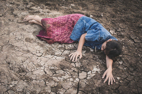 Sad girl tired and exhausted on cracked dry ground , Concept drought and shortage of water crisis