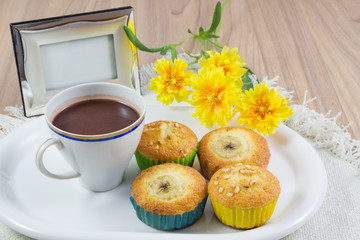 On a wooden table with a cup of hot cocoa, with a sweet dessert and a picture frame, Concept free time and happy.