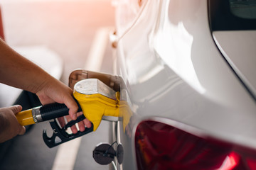 Man holding pumping gasoline fuel in car at gas station