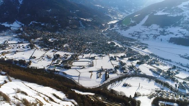 Aerial view of Bormio in winter, valley and mountains (Italian Alps) covered with snow, sunrise time - Italy from above, 4k UHD