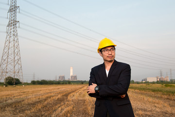 An engineer wear yellow hard hat and suite standing on field looking at camera