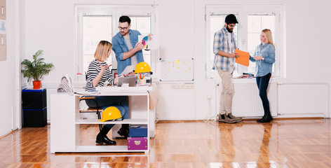 Team of young modern hardworking designers working together in the large bright office.