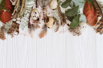 Happy Easter! Frame made with pink flowers, Easter eggs, red leafs, eucalyptus and branches on white background. Flat lay, top view, copy space