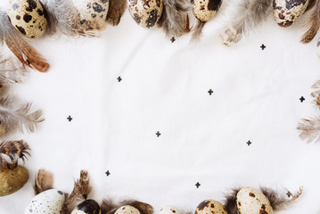 Easter quail eggs and feathers on white background. Flat lay, top view