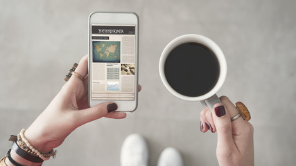 Woman holding mobile phone and reading news from screen other hand holding coffee cup - Powered by Adobe