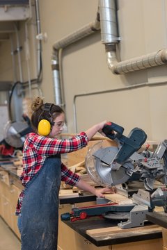 Female carpenter using grinder cutting machine