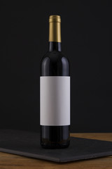 Isolated Red Wine Bottle in a Black, wood Background and White Label