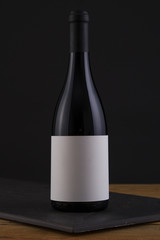 Isolated Red Wine Bottle in a Black, wood Background and White Label