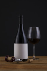Isolated Red Wine Bottle in a Black Background and Glass