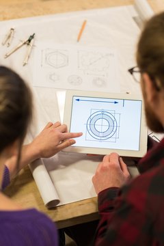 Male and female carpenters looking at plan on digital tablet