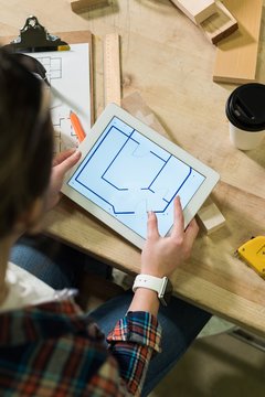 Female carpenter looking at plan on digital tablet