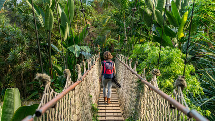 Hübsche Frau auf einer Hängebrücke in tropischem Wald