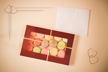 Macaroons in gift box and card on beige background