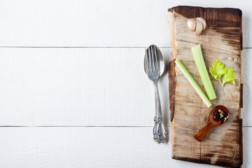Cooking background concept. Cutting board, spice and cutlery on white wooden background.