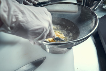 the chef prepares the dish in a frying pan. Hands close-up of chefs. Frying pan on the stove