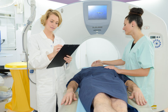 patient lying on mri machine while female doctor and nurse