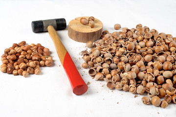 Crack hazelnuts with a hammer on the white table