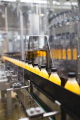 Naklejka premium Industrial factory indoors and machinery. Robotic factory line for processing and bottling of soda and orange juice bottles. Selective focus. Short depth of field.