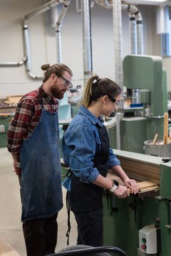 Male and female carpenters working together on vertical cutter