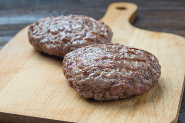 Two grilled hamburger patty on cutting board