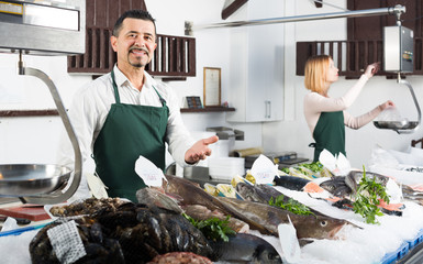 Two sellers in fish section of supermarket