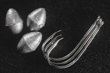 Fishing equipment: Hooks and fishing sinkers isolated on a dark background.