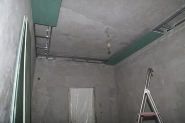 Fixing plaster boards at the ceiling of a house under construction.