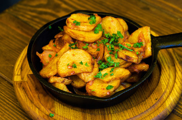 baked fried potatoes with garlic on wooden table background