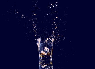 Isolated shot of whiskey with splash on black background, brandy in a glass